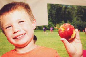 A kid posing after eating an apple during his summer camp in Marlborough, MA