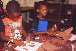 Two kids crafting something using paper and cardboard at a YMCA camp in Central Massachusetts