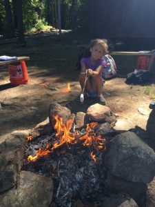 A young girl barbequing a marshmallow on a bonfire during YMCA camp in Central Massachusetts