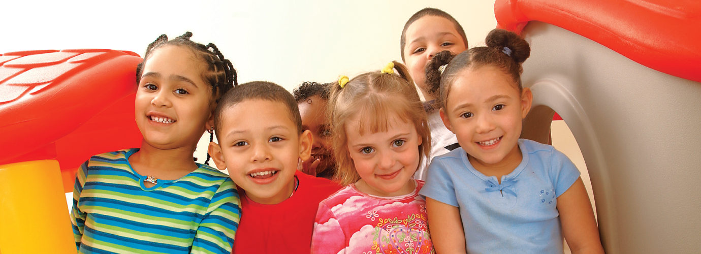 A group of children smiling while posing next to a playset in Central Massachusetts.